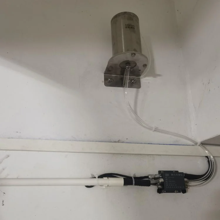 储液罐安装在墙面并通过管路连接水准测点的现场照片